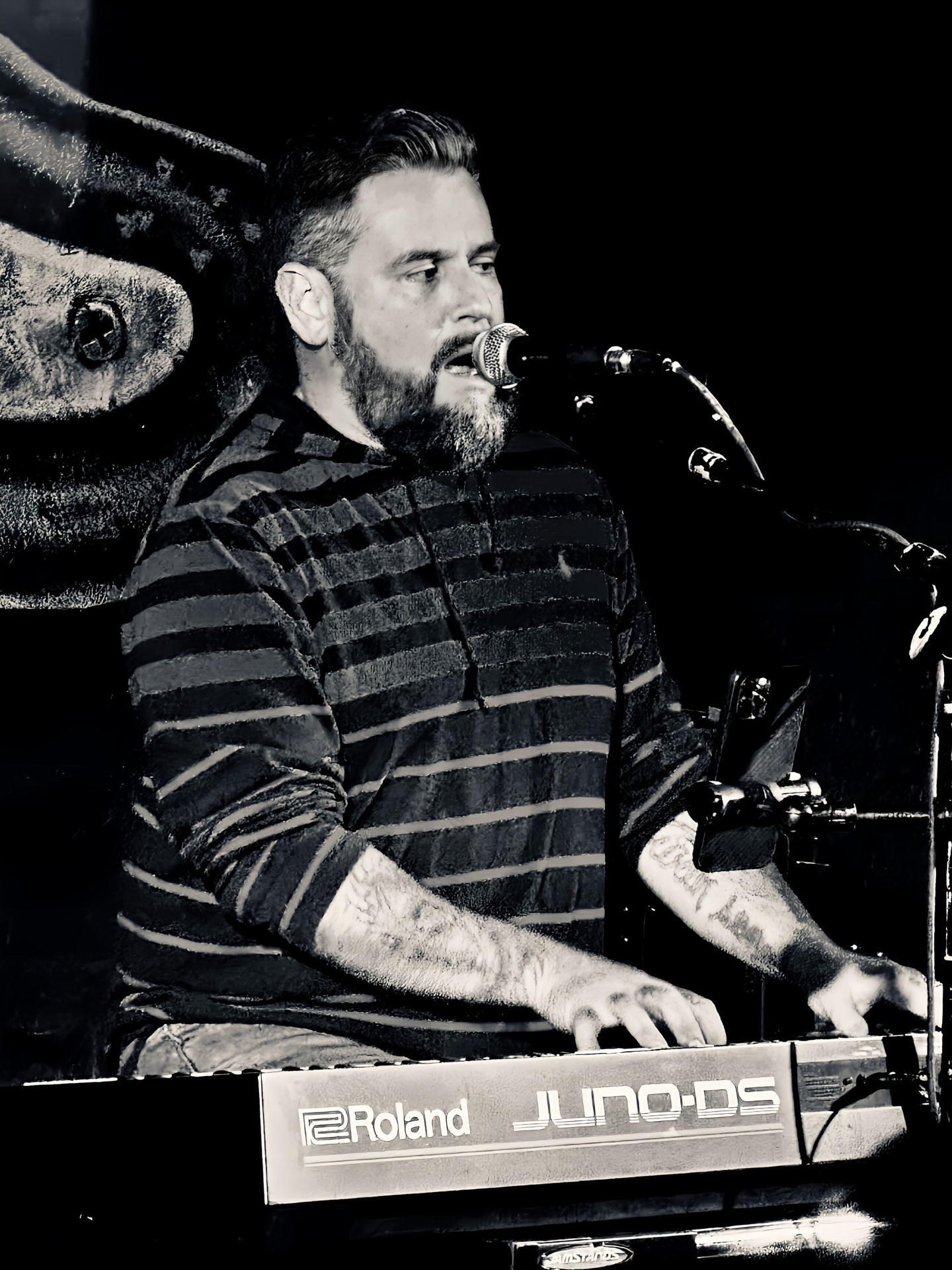 Black and white shot of Dan singing at the Roland Juno