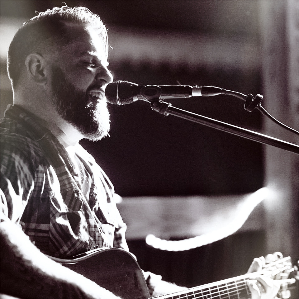 Black and white portrait of Dan singing into the mic