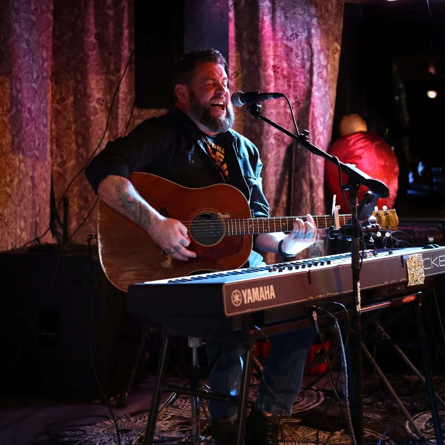 Dan singing wide open with acoustic guitar behind the keyboard