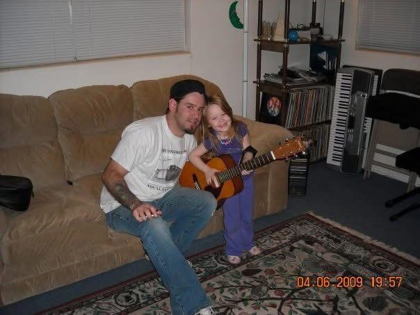 Dan teaching his young daughter guitar at home