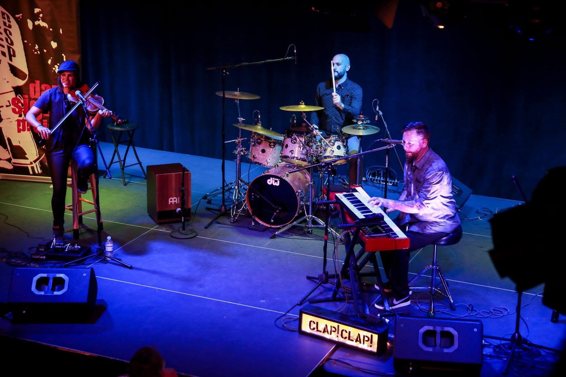 Dan Signor performing with violinist and drummer on stage