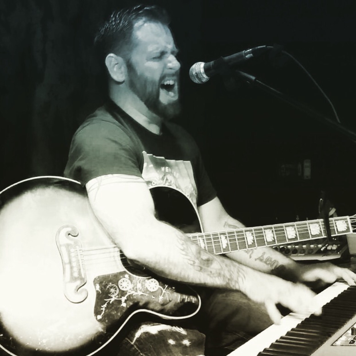 Dan Signor singing with guitar in black and white